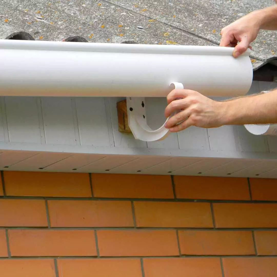 Hargreaves Contracting specialist in Lancashire installing gutters with a plastic support against a red brick wall